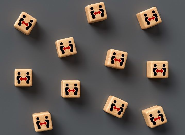 A number of separated wooden blocks with drawings of social distancing between two people on them.