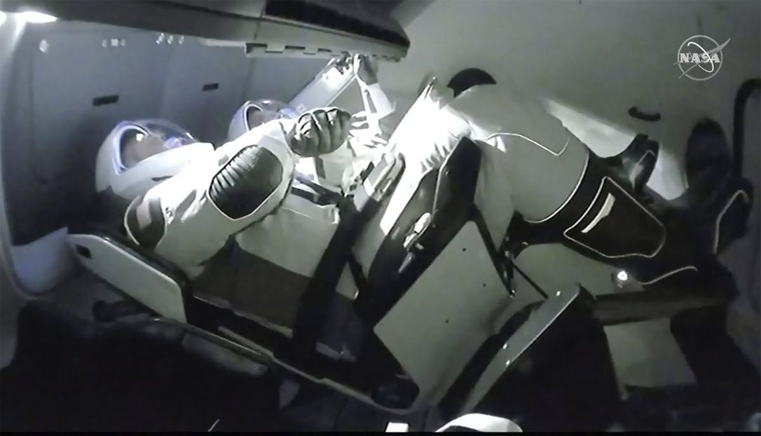 In this image taken from NASA TV video, the SpaceX Dragon crew capsule, with NASA astronauts Doug Hurley, left, and Robert Behnken aboard, docks with the International Space Station on Sunday. It was the first time a privately built and owned spacecraft carried astronauts to the orbiting lab in its nearly 20 years.