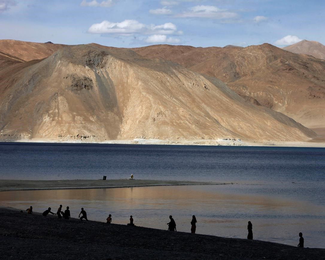 In this July 22, 2011 file photo, people stand by the banks of the Pangong Lake, near the India-China border in Ladakh, India.Indian officials say Indian and Chinese soldiers are in a bitter standoff in the remote and picturesque Ladakh region, with the two countries amassing soldiers and machinery near the tense frontier. The officials said the standoff began in early May when large contingents of Chinese soldiers entered deep inside Indian-controlled territory at three places in Ladakh, erecting tents and posts.
