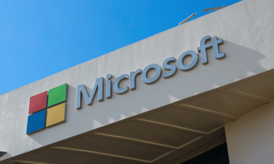 The Microsoft logo displayed on an office building under a blue sky.