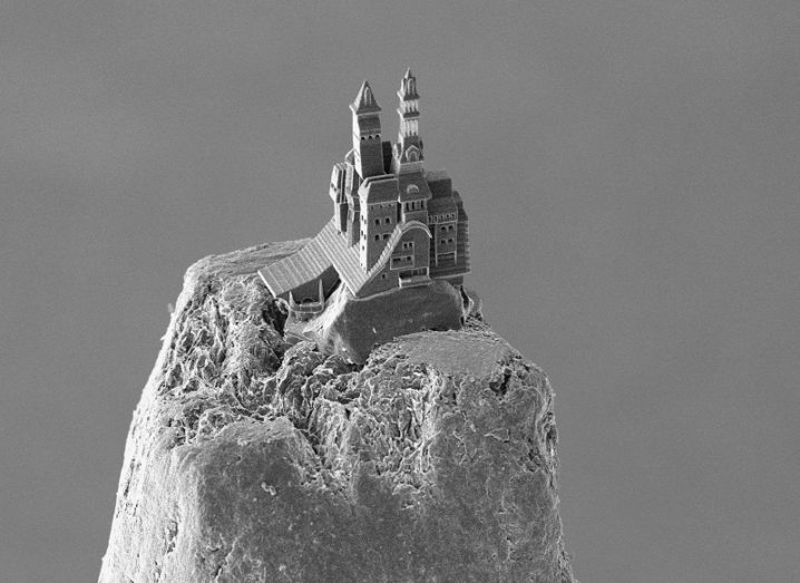 Black and white image of a 3D-printed castle on top of a pencil point.