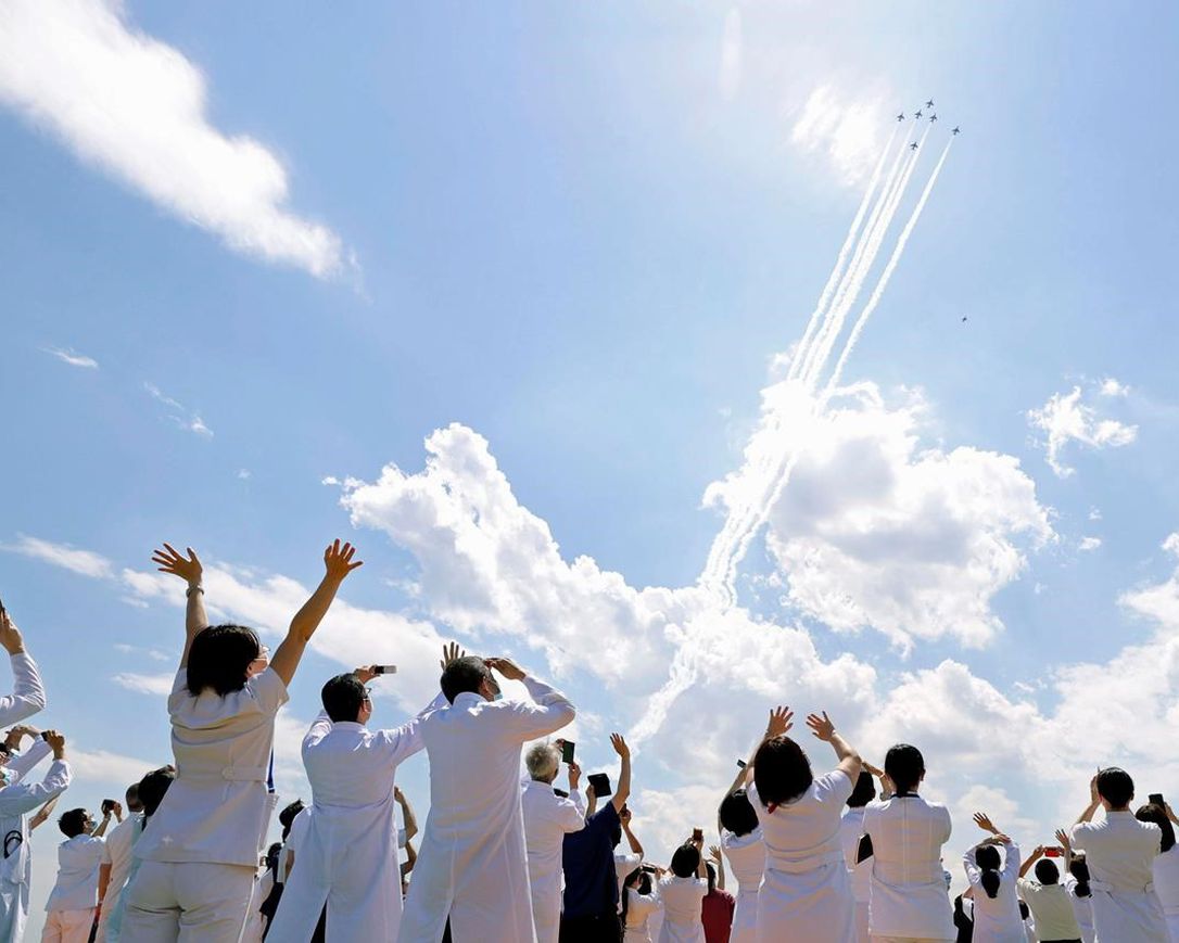 Blue Impulse of the Japan Air Self-Defense Force fly over medical workers of Self-Defense Forces Central Hospital in Tokyo, Friday, May 29, 2020, in Tokyo. A Japanese Air Self-Defense Force’s aerobatics team performed a demonstration flight to express support and gratitude for medical workers. The six Blue Impulse aircraft flew for about 20 minutes over Tokyo to thank for doctors, nurses and other medical staff.
