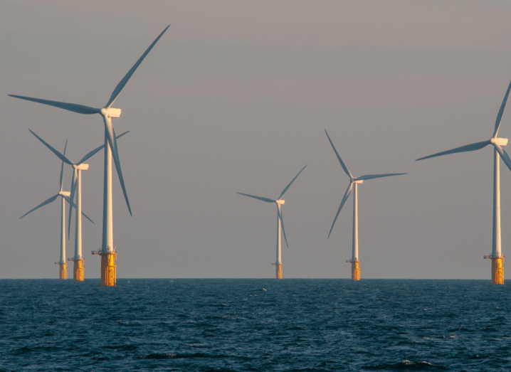 An offshore windfarm in a dark sea with seven turbines visible in the photograph.