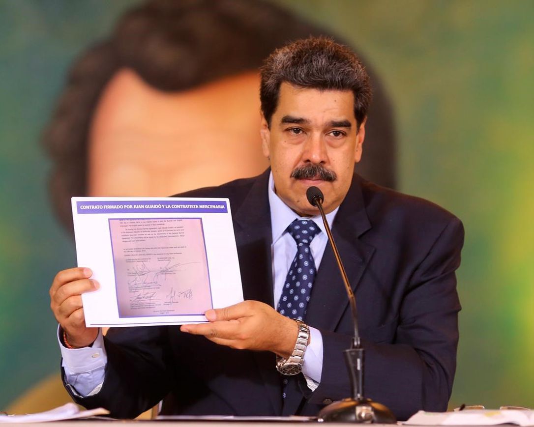 In this photo released by the Venezuela‚Äôs Miraflores presidential press office, President Nicolas Maduro accuses opposition leader Juan Guaido of being behind a military raid designed to oust him, as he holds a copy of a written agreement that allegedly bears Guaido‚Äôs signature as evidence, during an online press conference in Caracas, Venezuela, Wednesday, May 6, 2020.