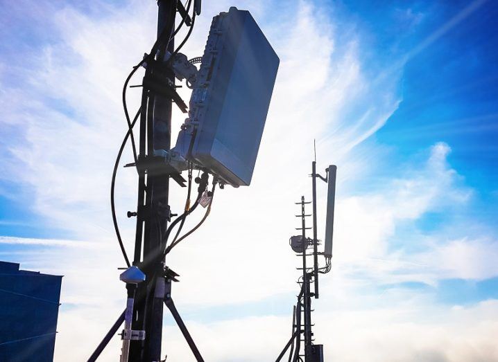 Silhouette of 5G base stations against a sunny background with clouds.