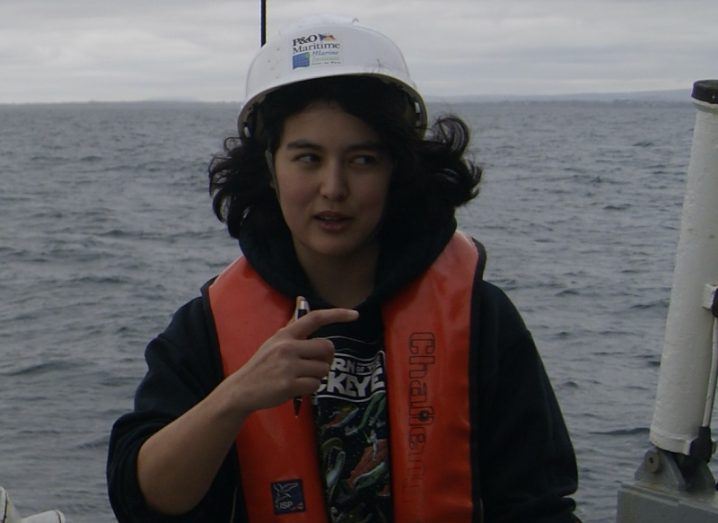 Elena Pagter wearing a lifejacket and a white hardhat on board a research vessel on the ocean.