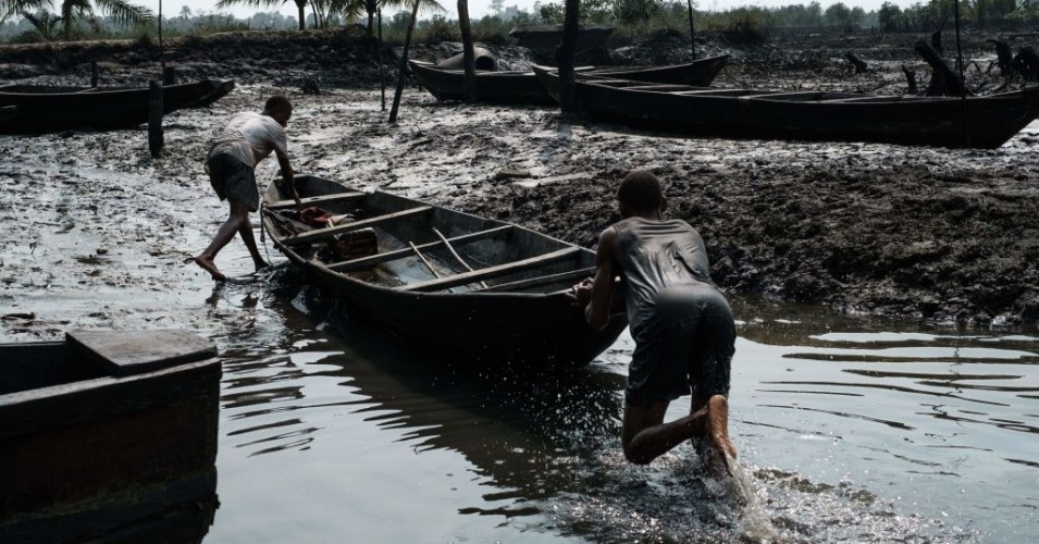 Fisherman push their boat during low tide on oily mud in the river at Ogoniland's village of K-Dere, near Bodo, which is part of the Niger Delta region, on February 20, 2019. -Decades of oil spills has left the Ogoniland region in southern Nigeria an environmental disaster zone. (Photo: should read YASUYOSHI CHIBA/AFP via Getty Images)
