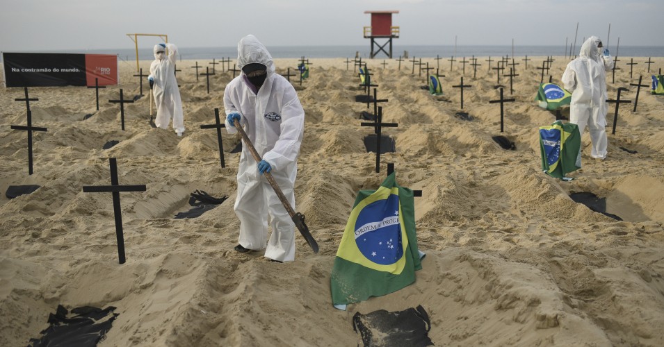 Protesters in protective gear dig mock graves symbolizing deaths due to Covid-19 to protest against the Brazilian government's handling of the pandemic on June 11, 2020 at Copacabana beach in Rio de Janeiro, Brazil. (Photo: Fabio Alarico Teixeira/Anadolu Agency via Getty Images)
