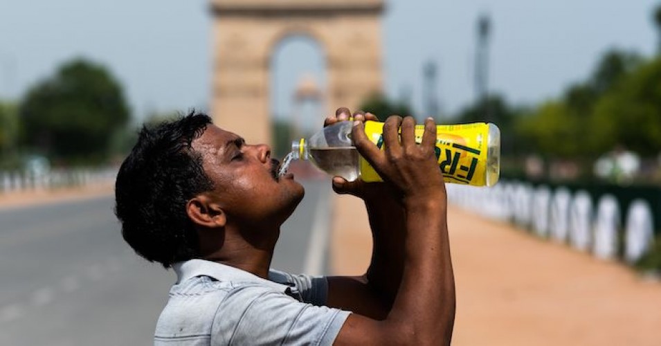 A worker quenches his thirst with water from a bottle taking a break from cleaning weeds from a park near India Gate amid rising temperatures in New Delhi on May 27, 2020.