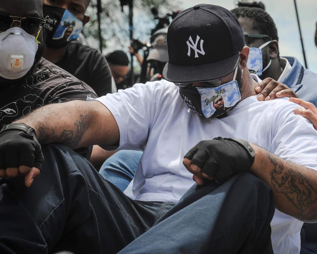 An emotional Terrence Floyd is comforted as he sits at the spot at the intersection of 38th Street and Chicago Avenue, Minneapolis, Minn., where his brother George Floyd, encountered police and died while in their custody, Monday, June 1, 2020.