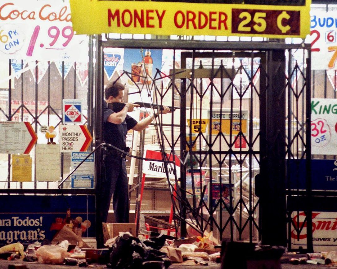 In this April 30, 1992 file photo, a Los Angeles police officer takes aim at someone attempting to steal something from a market in Los Angeles during the second night of rioting in the city in response to the acquittal of four police officers in the videotaped beating of Rodney King.