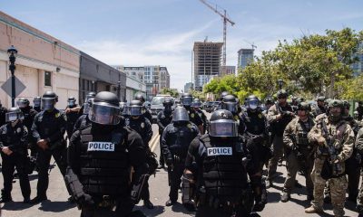 San Diego Police officers (L) in riot gear and a special tactics group (R) face-off with demonstrators in downtown San Diego, California as people gather to protest against the death of Minneapolis man George Floyd.