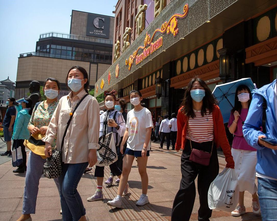 People wearing face masks to protect against the new coronavirus walk outside of a shopping mall at a pedestran shopping street in Beijing, Saturday, June 6, 2020. China's capital is lowering its emergency response level to the second-lowest starting Saturday for the coronavirus pandemic. That will lift most restrictions on people traveling to Beijing from Wuhan and surrounding Hubei province, where the virus first appeared late last year.