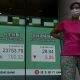 A woman wearing a face mask walks past a bank electronic board showing the Hong Kong share index at Hong Kong Stock Exchange Monday, June 1, 2020. Asian stock markets have rebounded after U.S. President Donald Trump avoided reigniting a trade war with China amid tension.