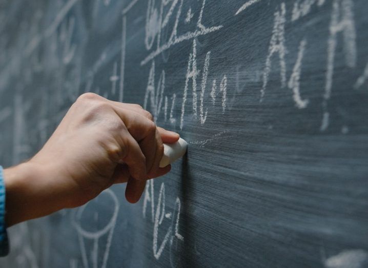 Hand writing maths formulae on a chalkboard.