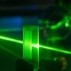Green laser shining through a glass block in a quantum research lab.