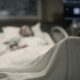 Blurred image of a woman in a hospital bed.