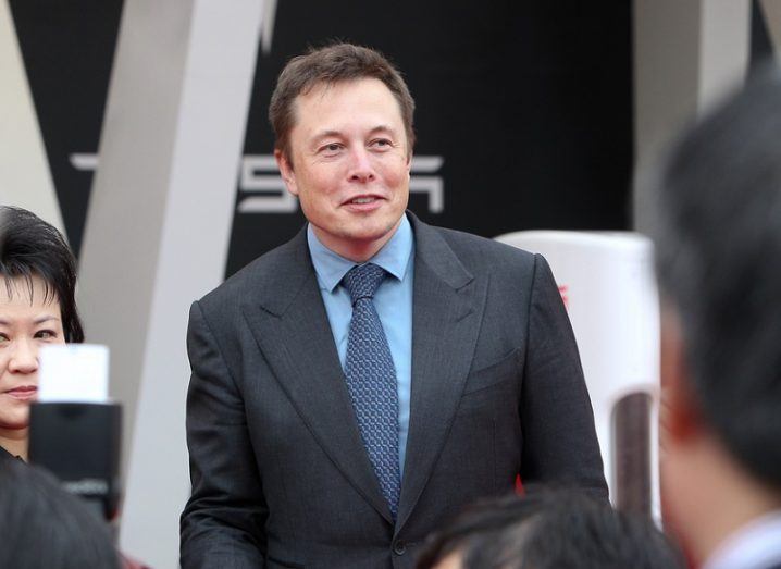 Elon Musk in a dark suit and blue shirt at a Tesla event.